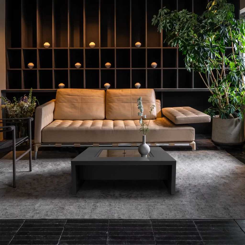 Contemporary fire pit table in a natural finish on a patio with a leather sofa.